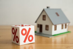 Blocks percentage sign with house model background. Central bank FED control interest rate increase or decrease effect to global economy, house price, monthly payment, buying home concept.