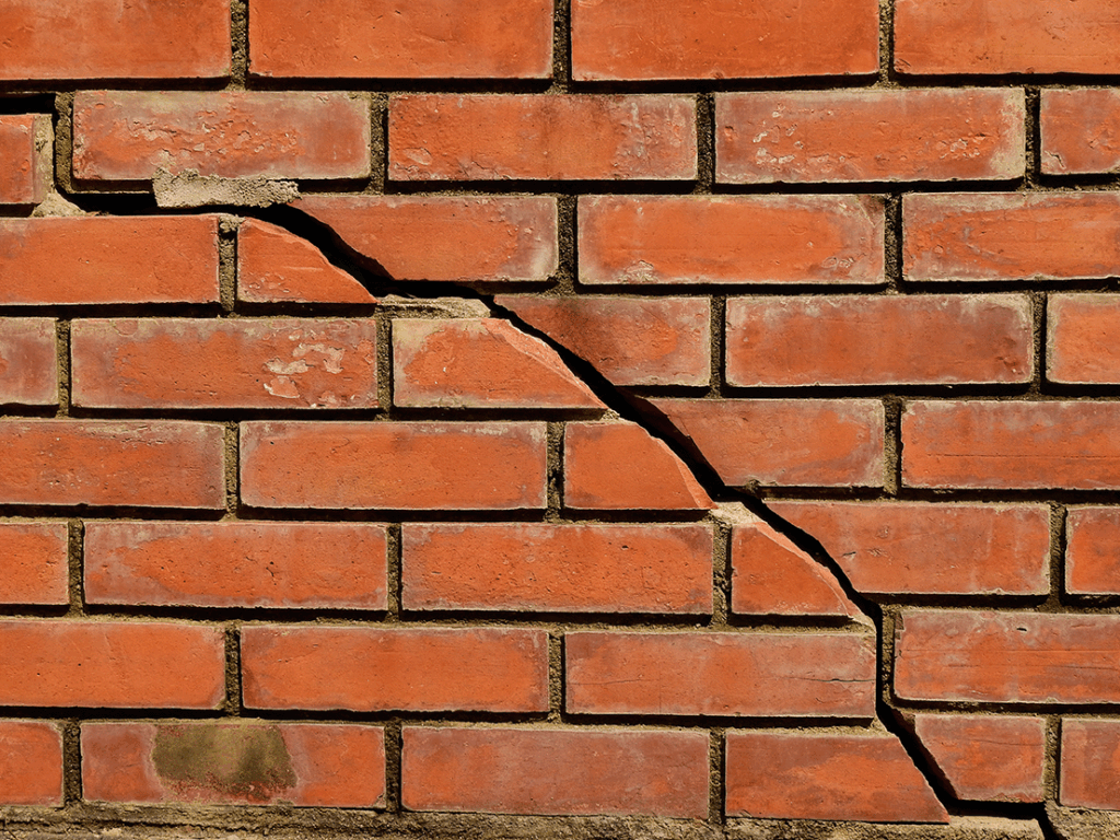 Cracked brick wall showing structural damage from construction works, highlighting the need for non-negligence cover or party wall insurance.